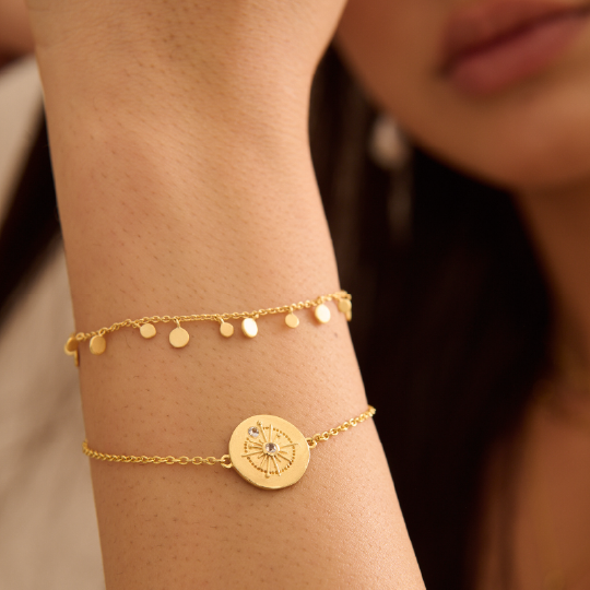 Gold bracelet with a circular design on a wrist against a blurred background