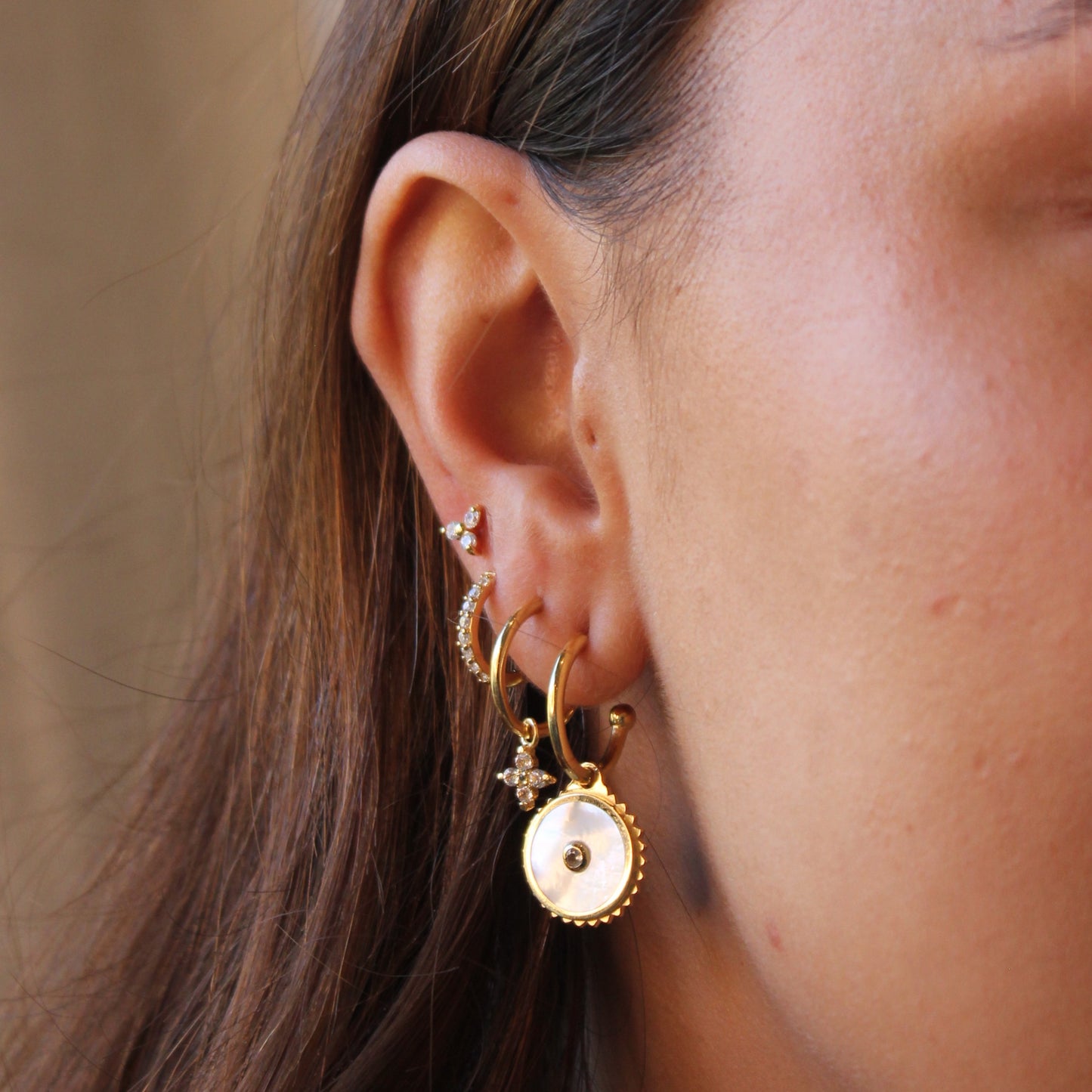 Close-up of an ear wearing gold hoop earrings with a blurred background