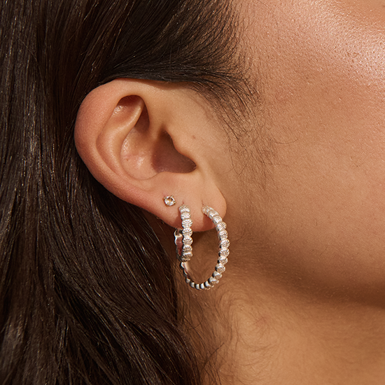 Close-up of an ear wearing hoop earrings with a blurred background