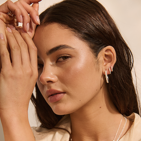 Close-up of a woman wearing earrings with a neutral background