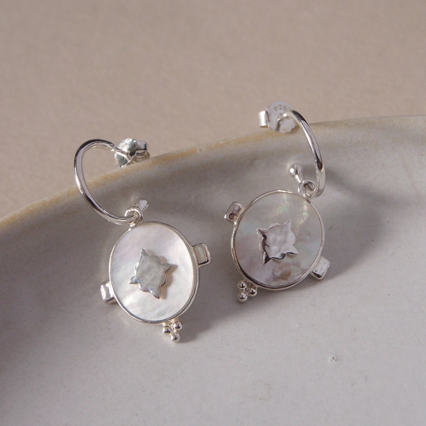 Handcrafted hoop earrings featuring luminous mother of pearl pendant. Crafted by skilled artisans.