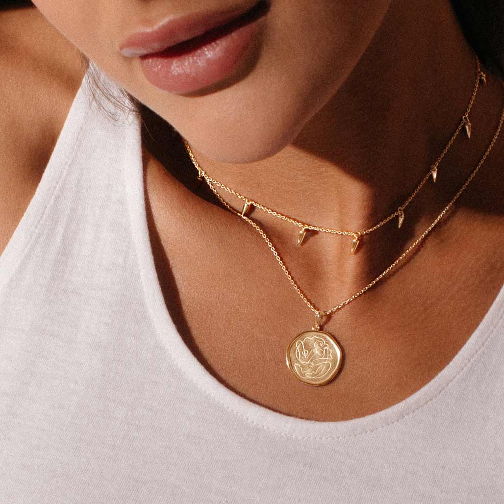 Handcrafted gold necklace celebrates the bond between mother and child. Artisan-made and intricately designed.