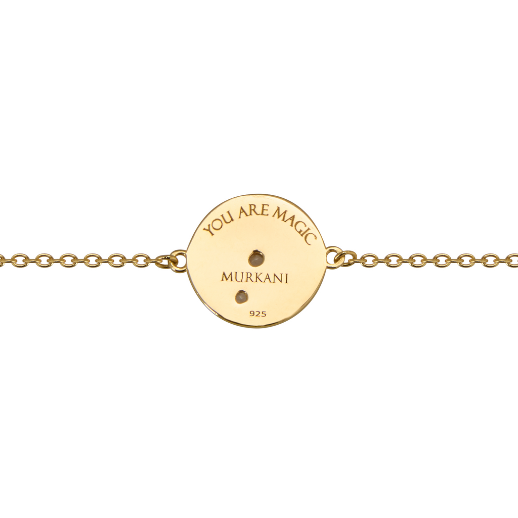 Gold bracelet with a round engraved disc on a white background