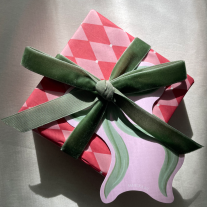 Gift wrapping with a green ribbon on a reflective surface