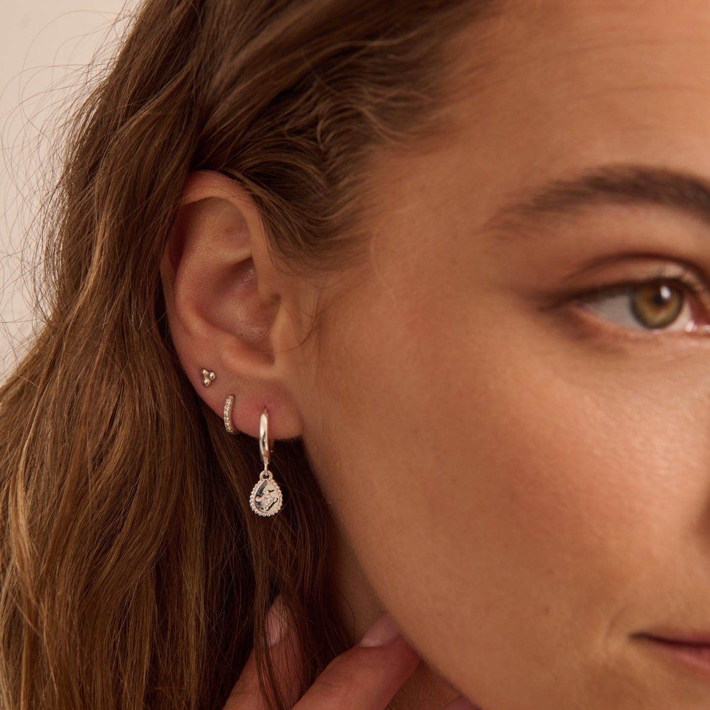 Close-up of a woman's ear with earrings and hair.