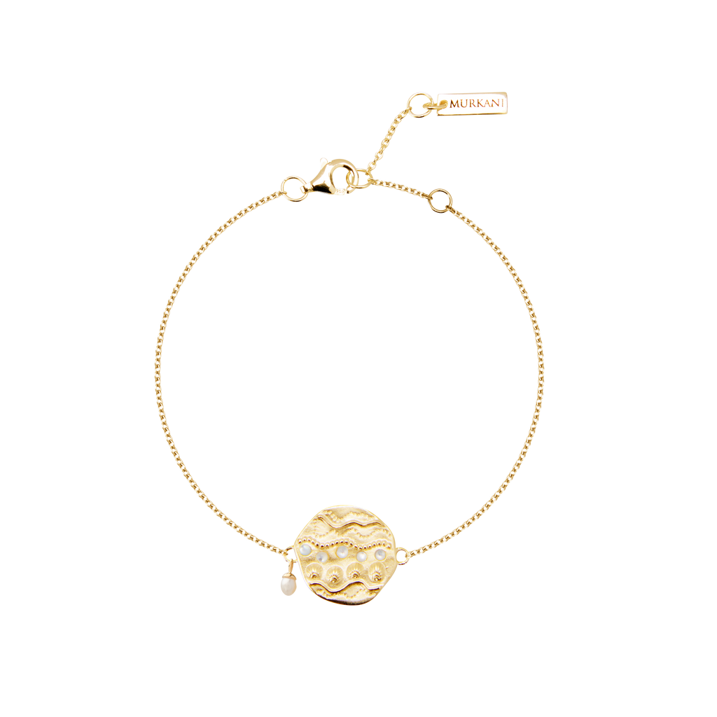 Gold bracelet with a decorative charm on a white background