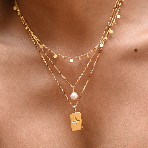Gold necklaces with pendants on a person's neck