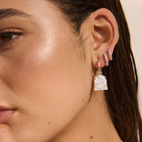 Close-up of a woman's ear with earrings on a neutral background