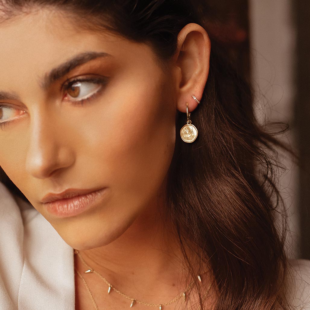 Gold empowerment hoop earrings, handcrafted by an artisan, showcasing intricate craftsmanship and attention to detail.