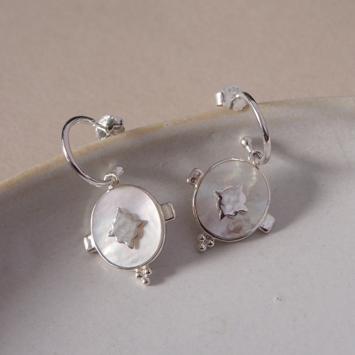 Handcrafted hoop earrings featuring luminous mother of pearl pendant. Crafted by skilled artisans. 