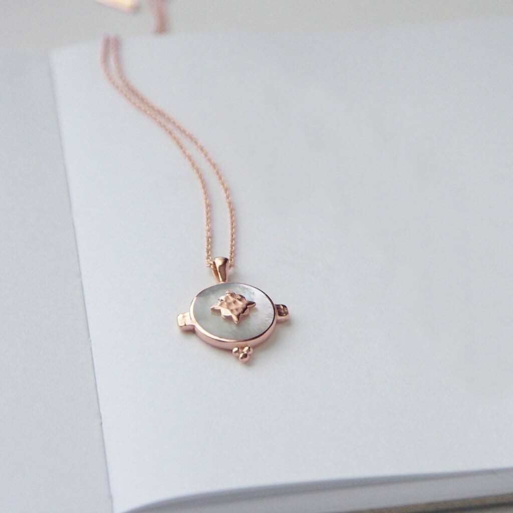 A handcrafted necklace featuring a mother of pearl pendant in a rose gold setting. An Artisan-made piece of jewellery.